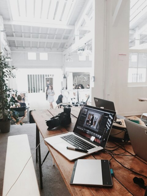 A busy workplace desk with computers and equipment in an bright office space